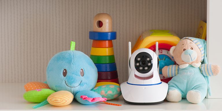 A piece of technology--a baby monitor--on a shelf with baby toys.